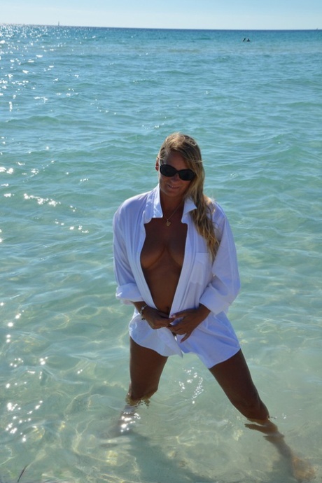 In a white shirt, a blonde amateur named Sweet Susi ventures into the ocean without clothing while naked and swimming in the waves.