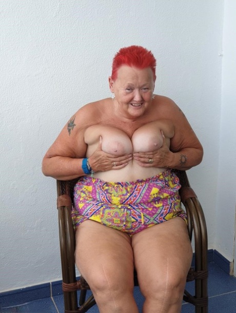 This obese nan, with red hair, exposes her pants on the balcony before taking it upon herself to pose inexplicably.
