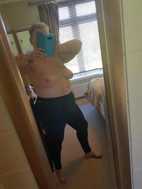 A fat lady with red hair goes naked and takes selfies at her home while on vacation.