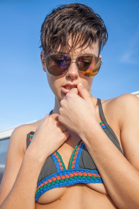 In a photo featuring a amateur girl with short hair freeing her pert tits from the bikini top, she shows off her sunglasses.