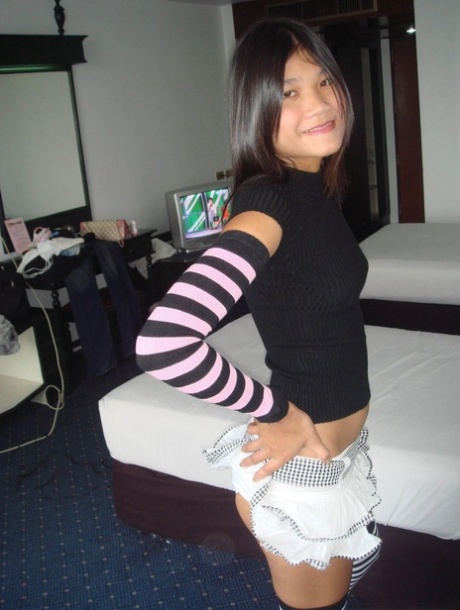 An Asian girl drinks a beer and removes her socks and thigh highs.