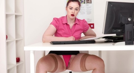 Deep redhead displays her thong while taking upskirt action beneath the table.