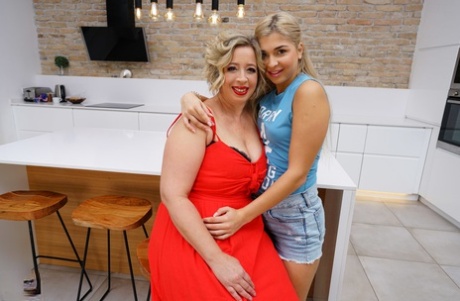 On a kitchen counter, older and younger blondes are seen having lesbian sex.