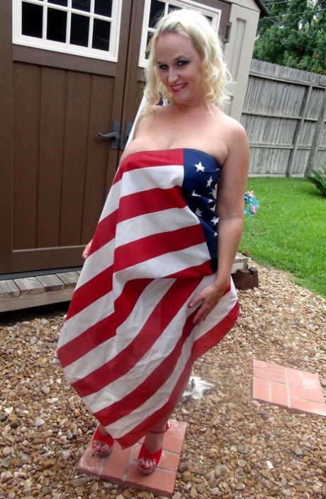 While wearing a red topless thong, blonde Dee Siren holds an American flag in her lap.