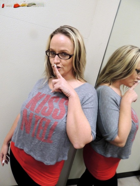 Dee Siren puts her pants down in a dressing room mirror.