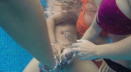 Older blond Sweet Susi and a girlfriend jerk a guy's dick underwater in a pool