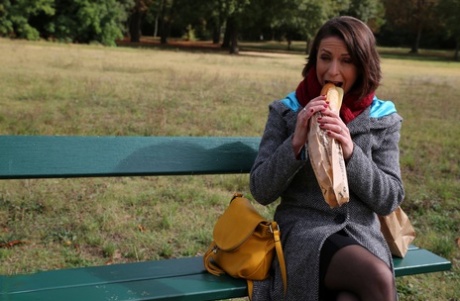 The older female takes a loaf of bread from an outdoor bench after being fouled vigorously.