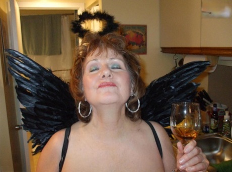An adult redhead named Busty Bliss licks a small bird with angel wings.