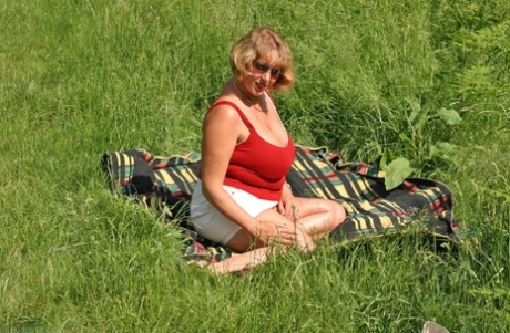 Fat and mature Curvy Claire exposes her large genitalia and buttocks in the field.