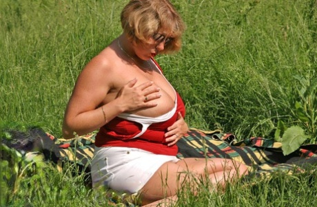 In a field where she can be found, Curvy Claire, a fat and mature woman, exposes her large breasts and buttocks.