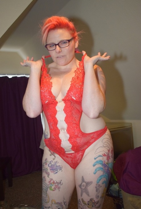Inked amateur slips off red lingerie to pose nude in glasses and heels