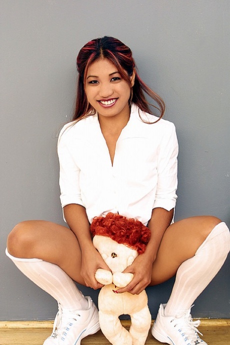 A young girl from India holds a stuffed animal and displays her vagina.