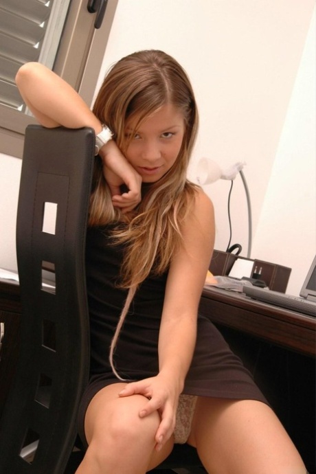 A charming girl exposes her racy clothes at her desk computer.