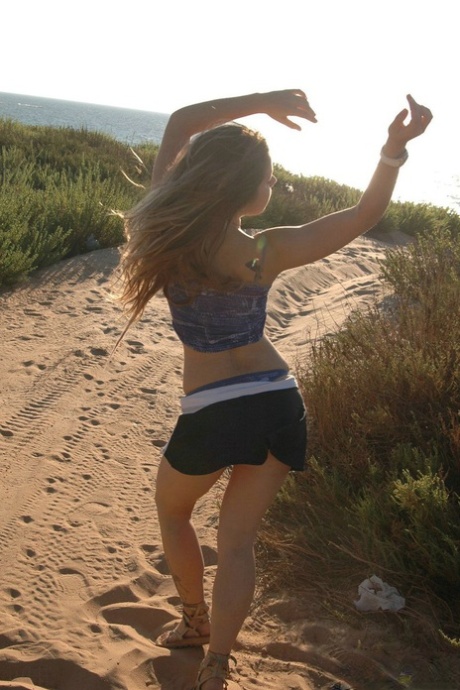 Pleasant little girl shows off tiny tits and her asses on sandy ground.