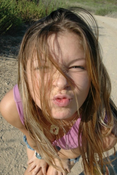 An unidentified girl lounging on a dirt road wearing only a denim miniskirt and panties.