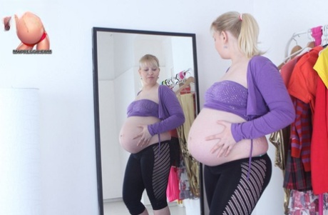 A pregnant blonde exposes herself to a mirror before masturbating.