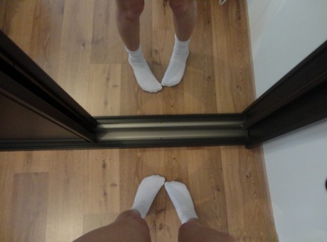 Wearing white socks, a young and brunette woman takes pictures of herself.