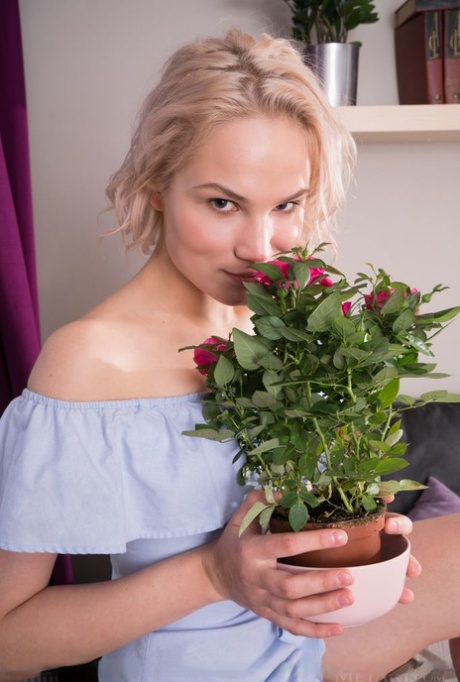 Fair skinned blonde teen Lilly Mai smells the flowers before getting naked