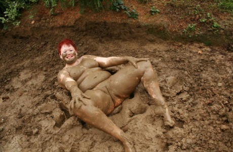 Older red-haired person, Valgasmic Exposed is seen rolling around in a dirty pool with no clothing on.