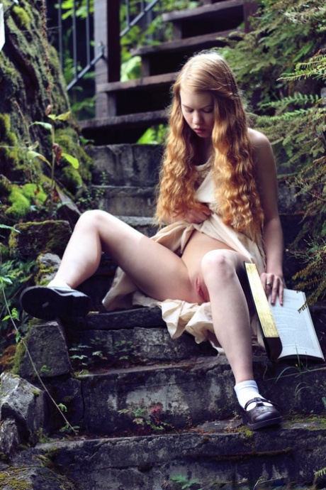 Young redhead Dolly Little exposes herself on garden steps while reading