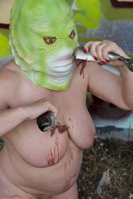 Despite being naked and not wearing any clothing, Speedy Bee enjoys eating a fish while wearing a costume mask.