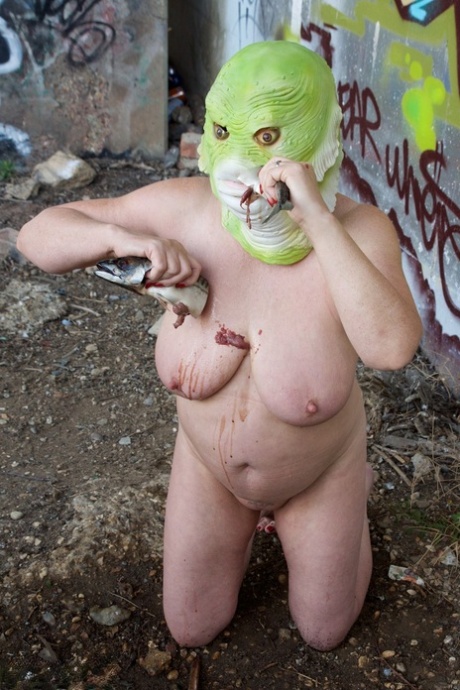 Naked British lady Speedy Bee eats a fish while wearing a costume mask