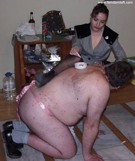 While smoking, a dominant woman causes an overweight naked man to be tortured.