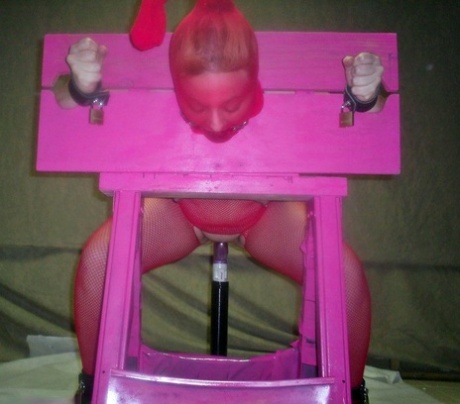 A ball gag is performed by a white woman in pink stocks while wearing a topless costume.