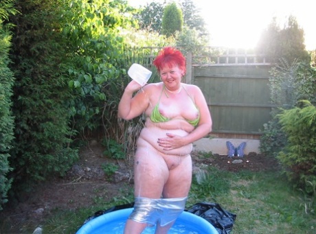 The old redheaded BBW Valgasmic Exposed enjoys a dildo in a wading pool.