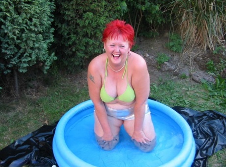 An older man named BBW Valgasmic Exposed engages in swimming activities while holding a dildo in a wading pool.