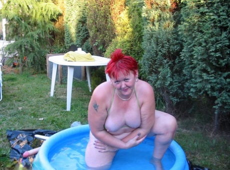 An older individual with red hair named BBW Valgasmic Exposed engages in swimming activities while holding their fists in a pool of dildo.