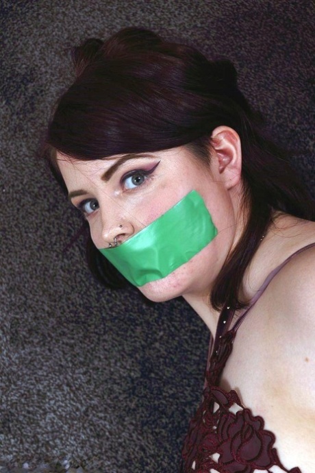 Dressed girl is tied up while a strip of tape is placed over her mouth and she remains silent.