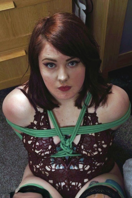 Clothed girl is silenced with a strip of tape over her mouth while tied up