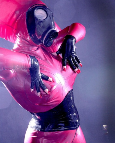 Caucasian female sports a gas mask while wearing a latex costume