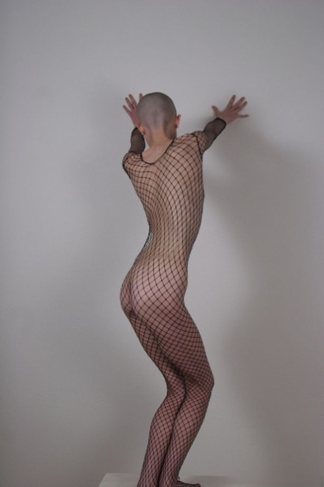 Solo Model With A Shaved Head Poses In A Fishnet Bodystocking