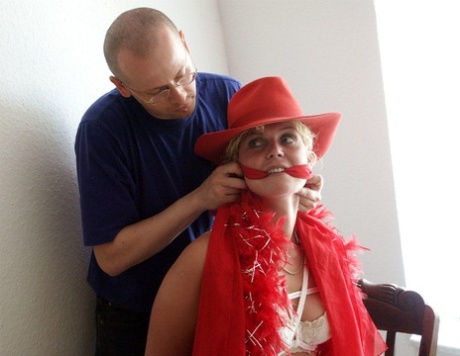 The blonde girl is secured to a chair and then subjected to being cleaved gagged.