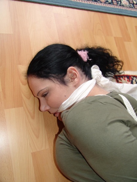 A dark haired girl is tied into her clothes with a rope and put on a cleave gag.