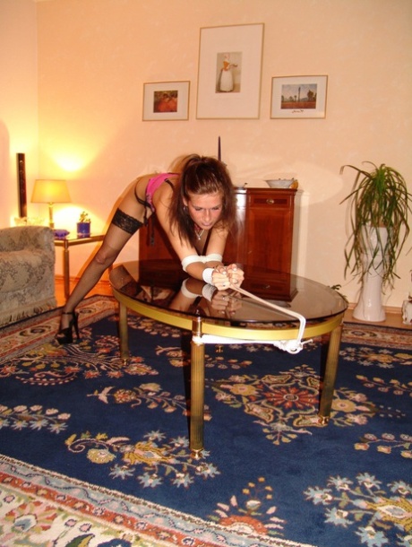 A white girl exhibits a cleave gag while being restrained with rope over a coffee table.