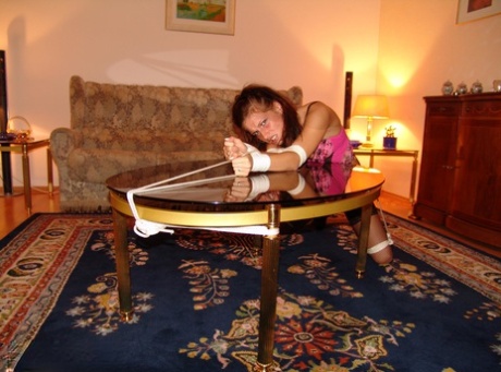 Rope tied over a coffee table: A white girl wears the ‘cleave gag’.