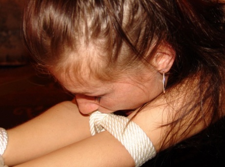 Using rope and her hair tied over the top of a coffee table, this Caucasian girl sports an open cleave gag.