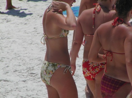 A sea of girls with tanned skin and tight bikinis are relaxing on the beach.