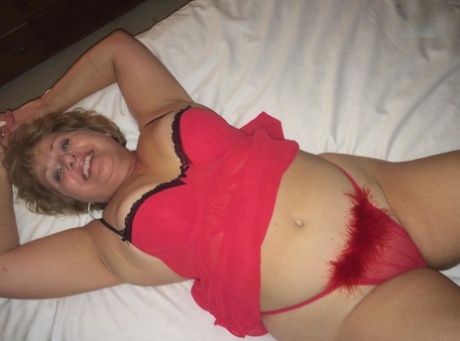 On a bed, Busty Bliss exposes her large breasts while wearing a Thong.