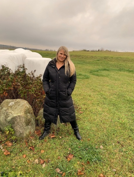 Sweet Susi, who is older and blonde, exposes herself in a field while wearing a winter coat.