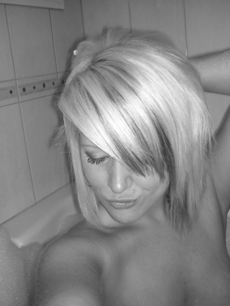 In the bathroom, a blonde girl displays her alluring ass while taking a selfie.