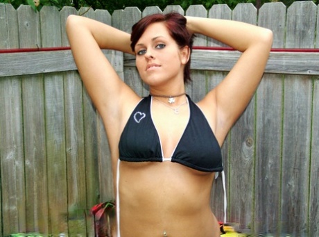 In the proximity of a pool, Roxy, an amateur girl, releases her firm tits from her bikini top.