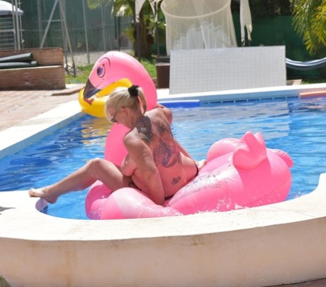 A tattooed, older woman named Melody shows her age without a top on an inflatable in a swimming pool.