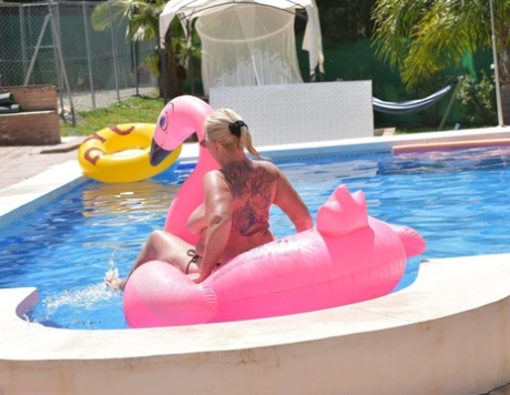 With her older tattooed body on top, Melody floats on an inflatable in the middle of a swimming pool.