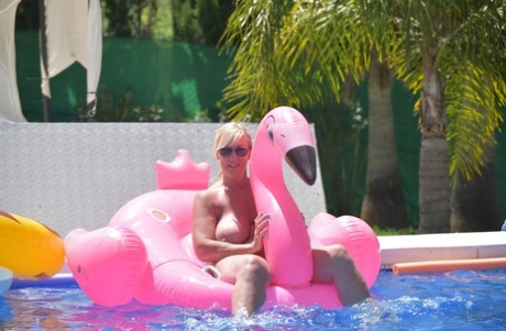 At the pool, Melody - an older woman with blonde tattoos and experience years of swimming without clothing on an inflatable boat.