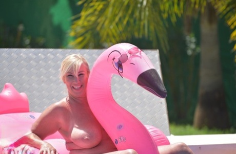 Melody, who has an older tattoo on her body, is seen with her hands naked in a swimming pool on an inflatable.