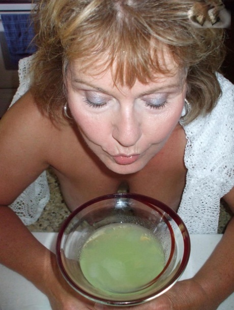 Busty Bliss, a young adult with breast development, flaunts her chest while drinking from an alcoholic beverage.